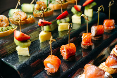 A variety of gourmet canapes with fresh toppings on a reflective black serving tray 