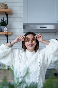 Portrait of young woman wearing sunglasses while standing against wall