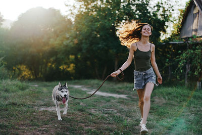 Portrait of young woman with dogs standing on field