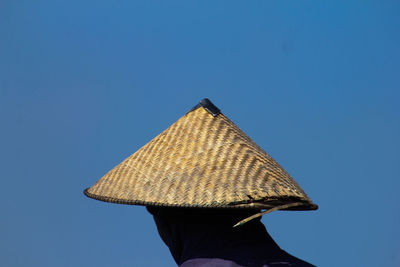 Rear view of man holding umbrella against clear blue sky