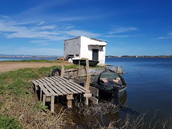 House by lake against sky
