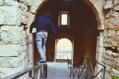 Man standing by window of old building