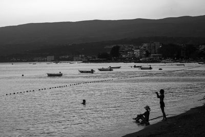 People on shore by sea against sky