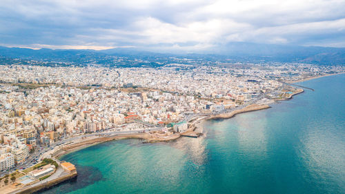 Aerial view of city against cloudy sky