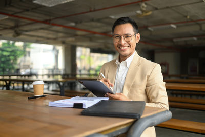 Portrait of businessman using laptop while standing in office