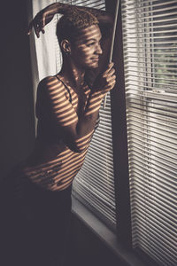 Smiling woman looking through window at home