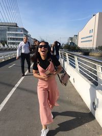 Woman laughing while walking on bridge in city