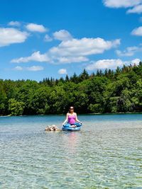 Woman sitting in lake against sky