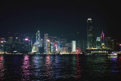Illuminated buildings in city against sky at night