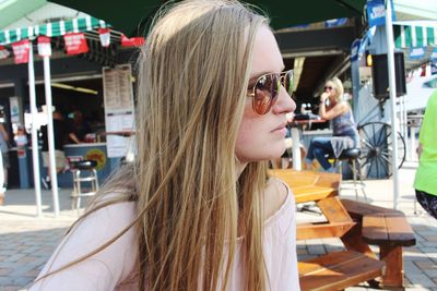 Thoughtful young woman wearing sunglasses while sitting at sidewalk cafe