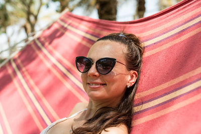 Portrait of woman wearing sunglasses while relaxing on hammock