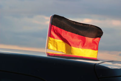 German flag on car against sky during sunset