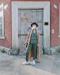 Full length portrait of woman standing outside house