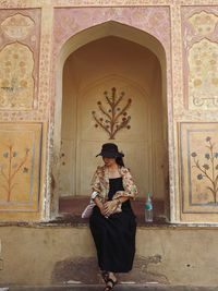 Full length of woman standing against door of building