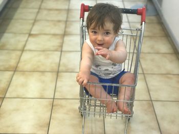 High angle portrait of happy baby boy sitting in shopping cart