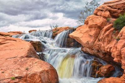 Scenic view of waterfall against sky