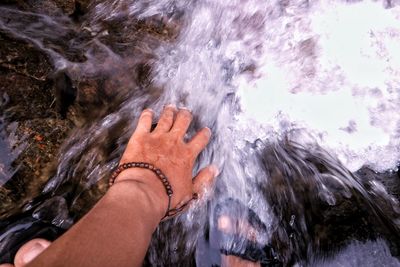 Low section of man standing in stream