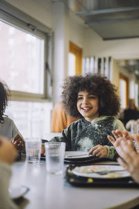 Smiling afro girl sitting at table during lunch break at school