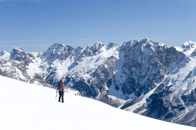 Man walking in the snow in front of the mountain range