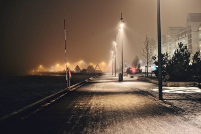 Illuminated street lights against sky at night