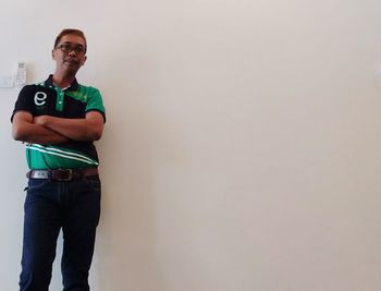 Portrait of young man standing against wall