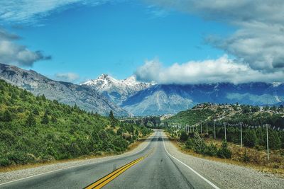 Road leading towards mountains against sky