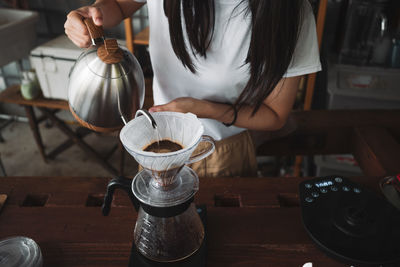 Midsection of woman having coffee at table