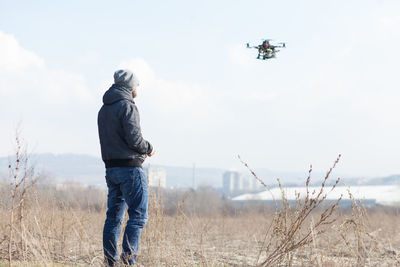 Man operating quadcopter against sky