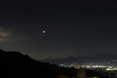 Illuminated cityscape against sky at night