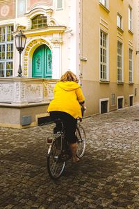 Rear view of woman riding bicycle on street