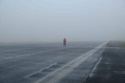 Rear view of man walking on road in foggy weather