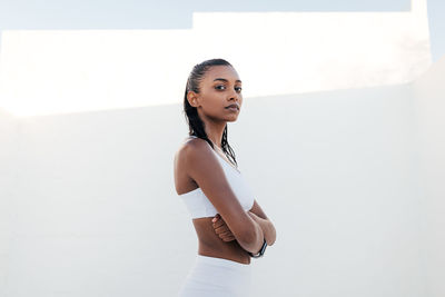 Portrait of young woman standing against wall