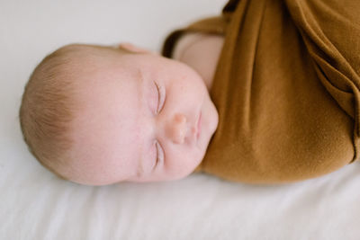 Closeup of newborn baby sleeping in brown swaddle