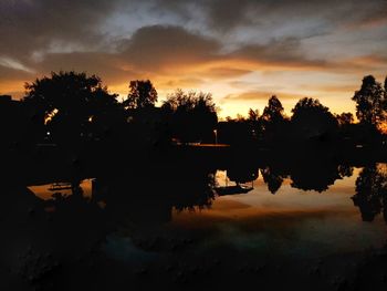 Silhouette trees by lake against sky during sunset