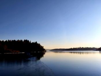 Scenic view of lake against clear sky at sunset