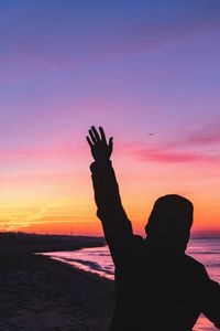 Silhouette man on beach against sky during sunset