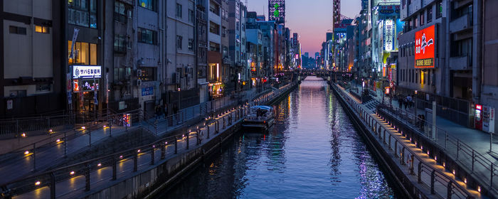 Panoramic view of canal amidst buildings in city at dusk