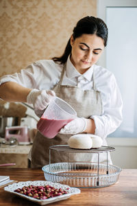 Mousse heart shape pink cake in hand of asian arabic woman pastry chef. mirror glaze cake. process