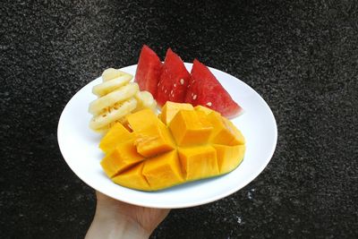 Close-up of hand holding tropical fruits in plate