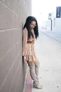Young woman standing against wall
