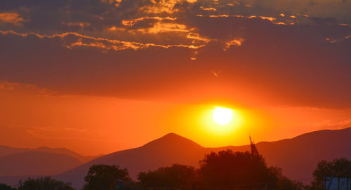Scenic view of silhouette mountains against romantic sky at sunset