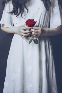 Midsection of couple holding red flower