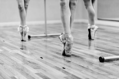 Low section of ballet dancers dancing on hardwood floor