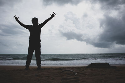 Silhouette man standing on beach against sky