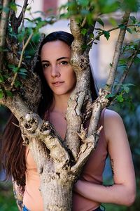 Portrait of young woman standing by tree