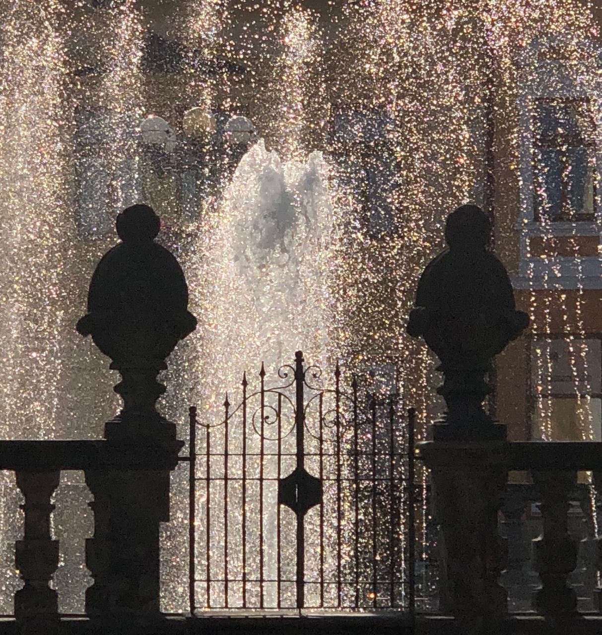 SILHOUETTE PEOPLE STANDING BY FOUNTAIN AGAINST SHADOW OF WATER