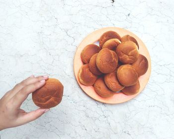 Cropped hand of person holding bread over marble