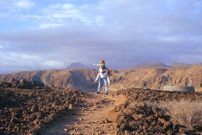 Rear view of man standing on mountain against sky