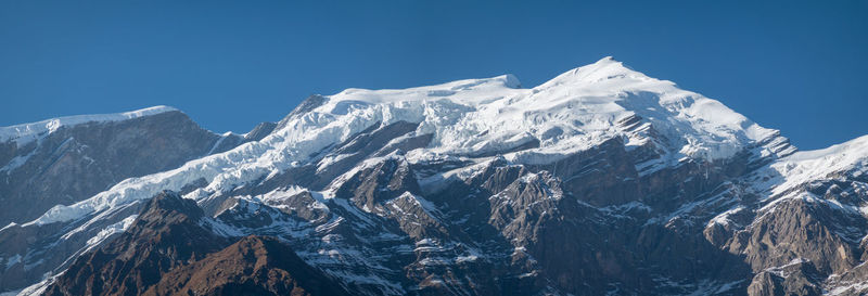 Scenic view of snowcapped mountains against clear blue sky