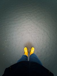 Low section of person standing on yellow shoes